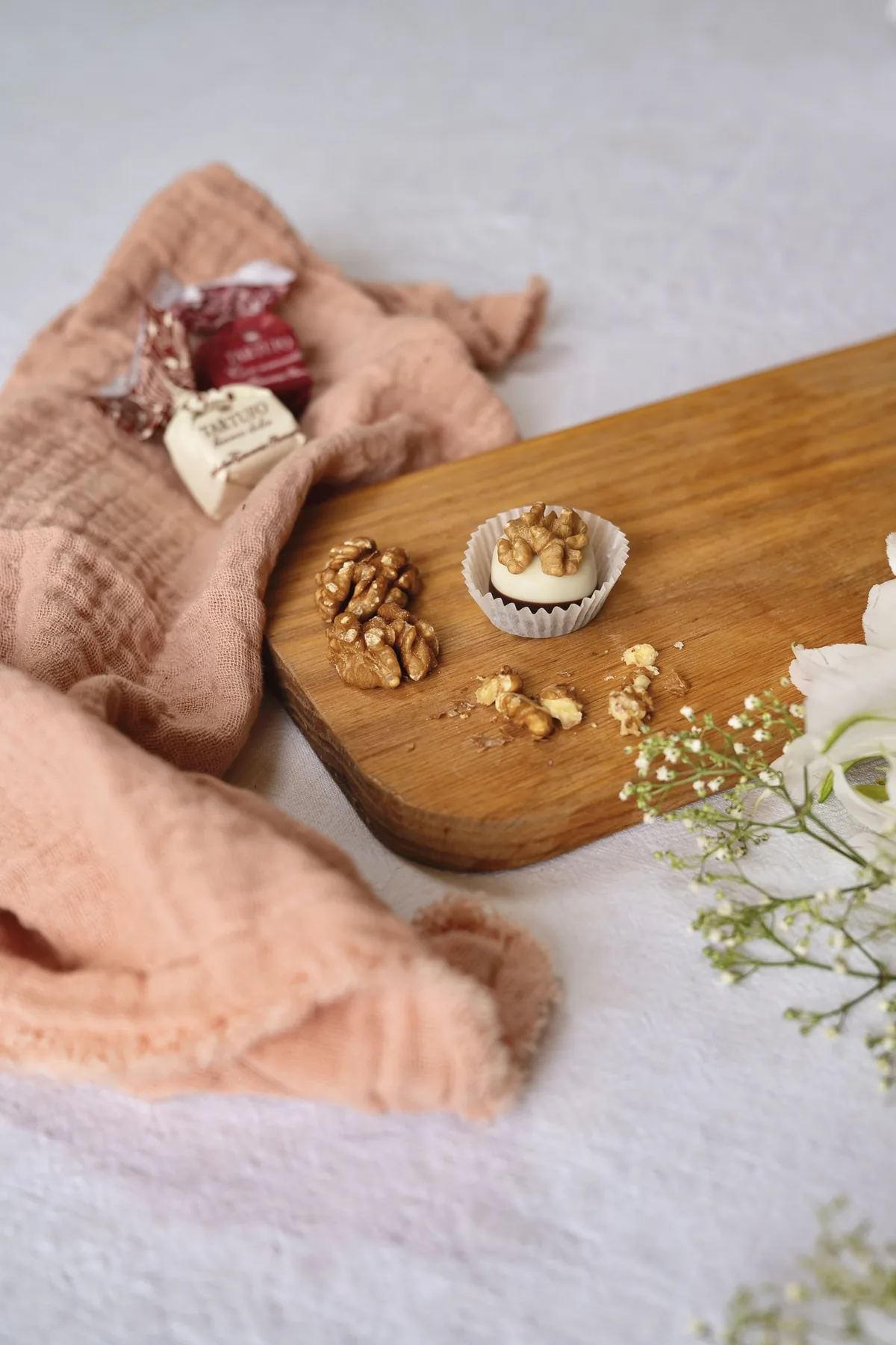 Pralinen auf einem Holzbrett mit Leinentuch und Blüten